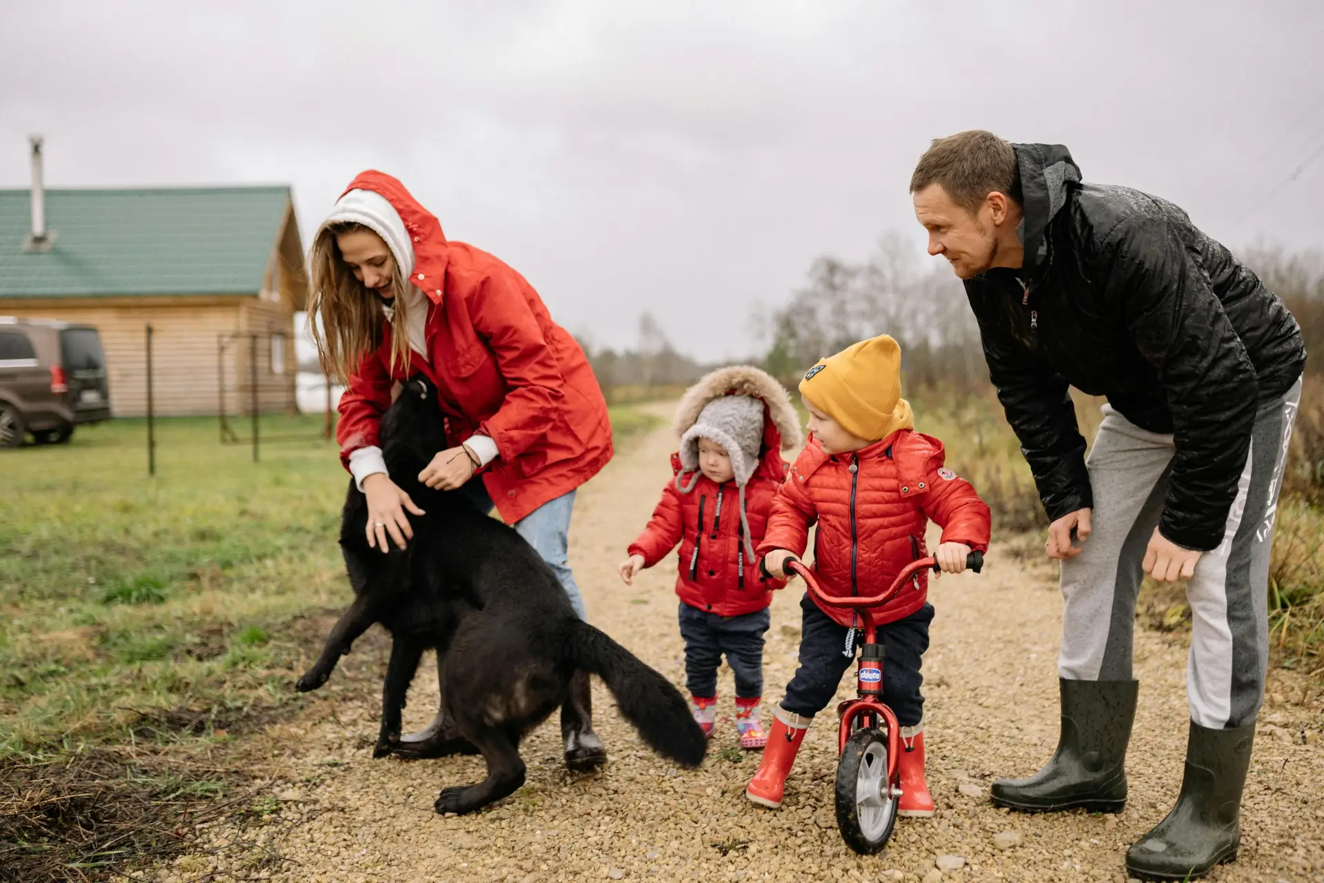 A family bonding outdoors with children playing and a pet dog in the countryside.